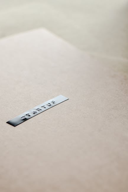 Etichetta metallica con la parola Startup su sfondo neutro, simbolo di progetti di imprenditorialità giovanile e futuro professionale.