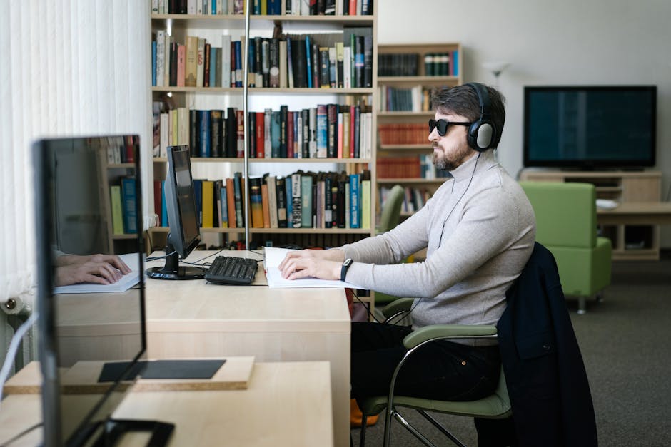 Persona non vedente utilizza computer con software accessibile e braille per studio e lavoro, supporto PEI e inclusione.