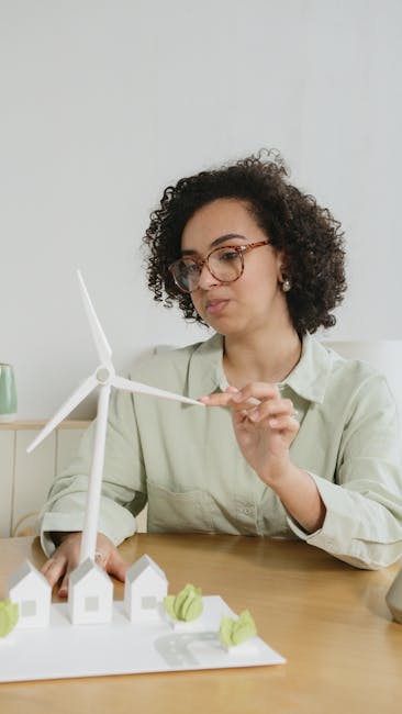Studentessa esamina modello di turbina eolica e case, apprendimento pratico per una valutazione efficace delle competenze