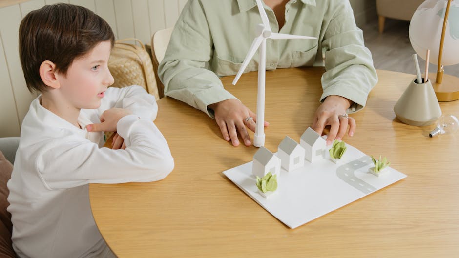 Bambino e adulto che studiano un modello di città sostenibile con case, strada e turbina eolica per l'innovazione