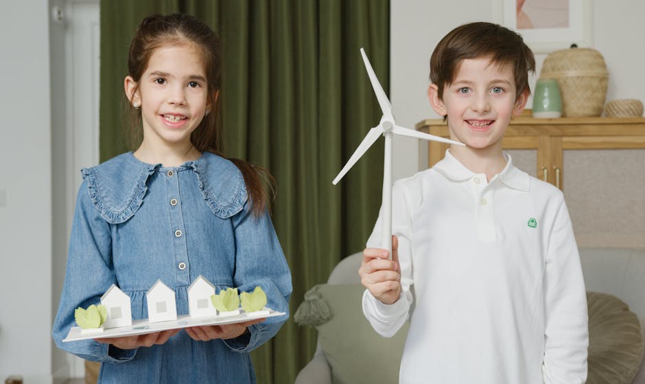 Bambini sorridenti con modellini di case e turbina eolica: progetti scolastici sull'energia rinnovabile per le future generazioni