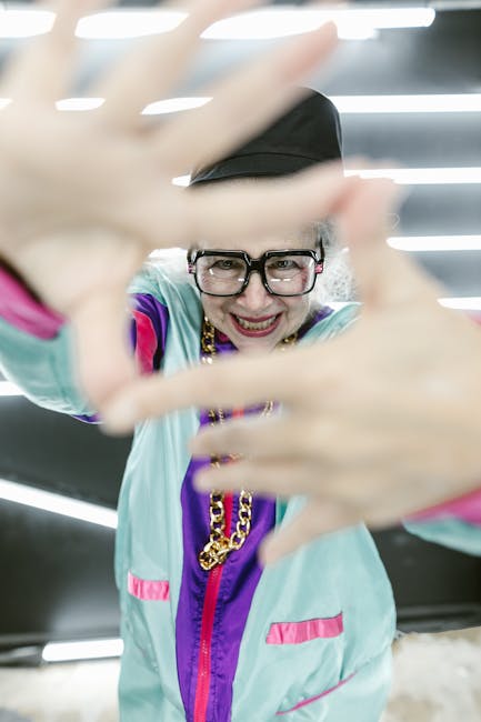 Donna anziana sorridente con abbigliamento colorato e catena d'oro, gesto di inquadratura, simbolo di vitalità e benessere unico