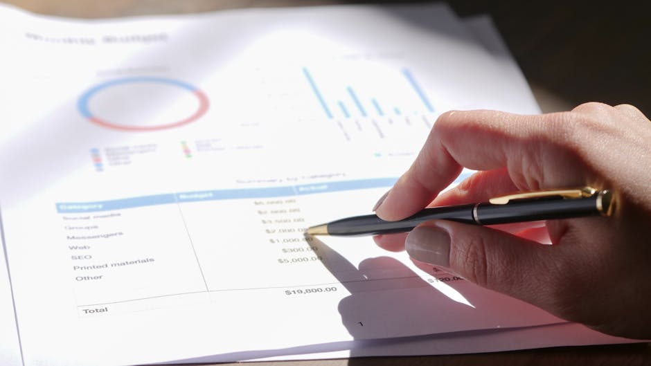 Analisi dei dati aziendali: mano con penna su report finanziario con grafici e tabelle per decisioni strategiche