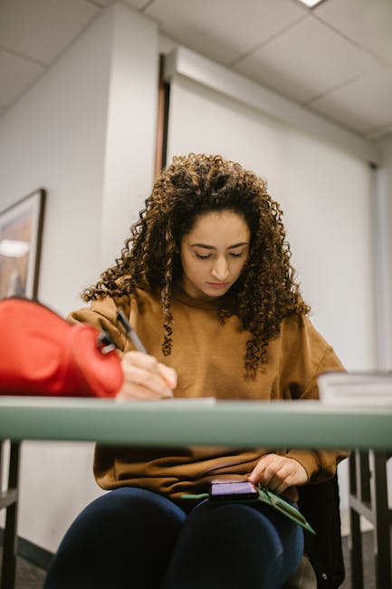 Studentessa concentrata che utilizza tecnologia e prende appunti in classe, esempio di istruzione moderna e innovazione didattica