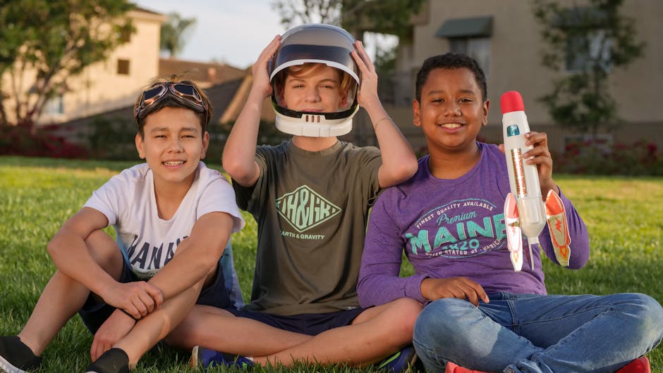 Tre bambini giocano all'aperto con un razzo e un casco da astronauta, promuovendo l'immaginazione e lo sviluppo sociale infantile.