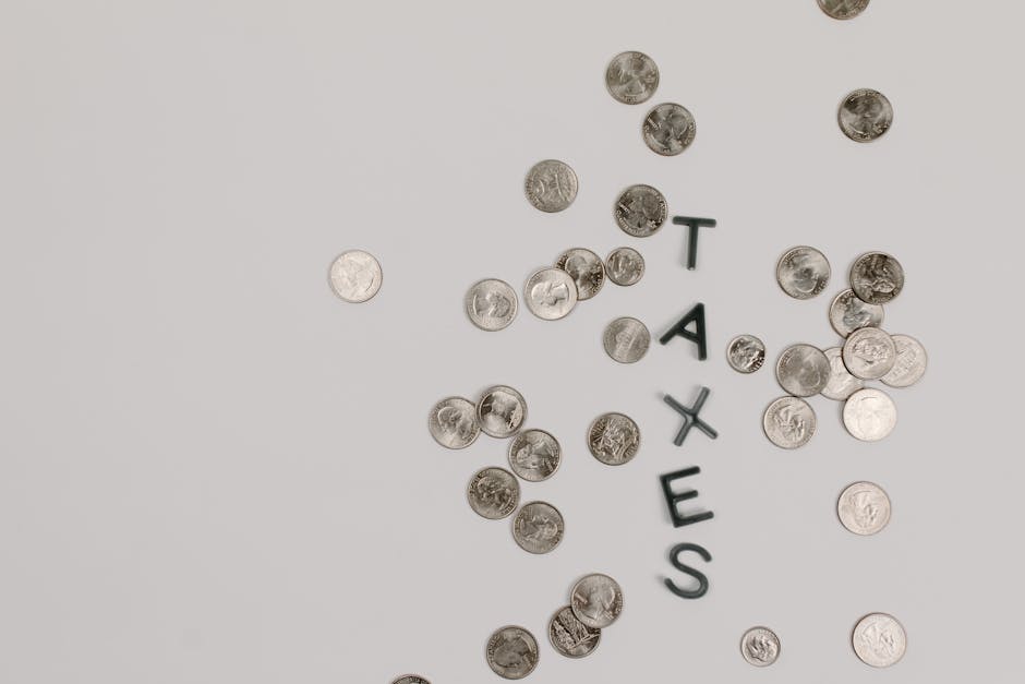 Monete sparse con la parola TASSE, illustrazione del piano economico del governo per la stabilità di bilancio e la stabilizzazione del debito.