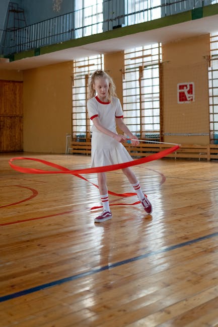 Ragazza che pratica ginnastica ritmica con nastro rosso in palestra scolastica, esempio di flessibilità didattica e organizzativa.