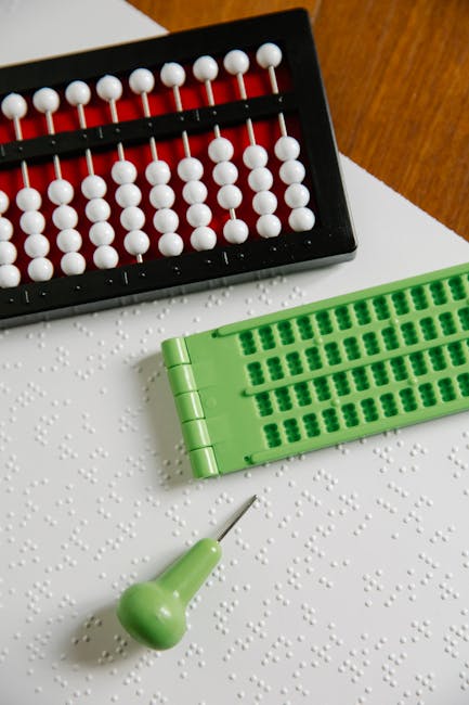 Strumenti per l'inclusione: pallottoliere, tavoletta braille e punteruolo su foglio con testo braille, adattamenti ragionevoli.