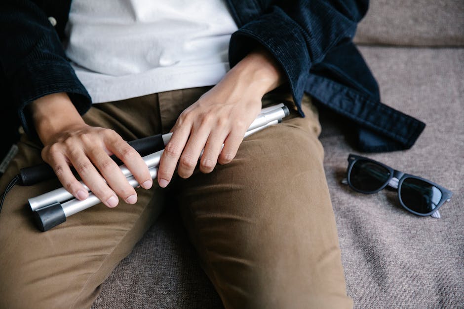 Persona non vedente con bastone bianco e occhiali da sole, metafora di resilienza e preparazione alla difesa della tesi.
