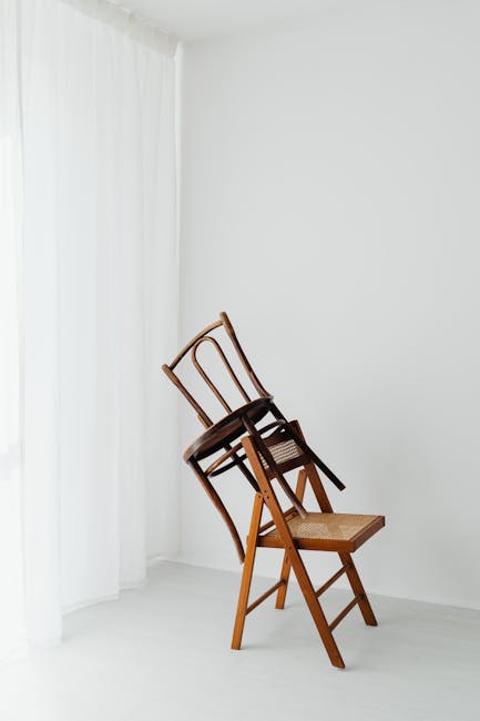 Due sedie di legno impilate in un angolo, concetto di angoli adiacenti e relazioni geometriche in un ambiente minimalista e luminoso.