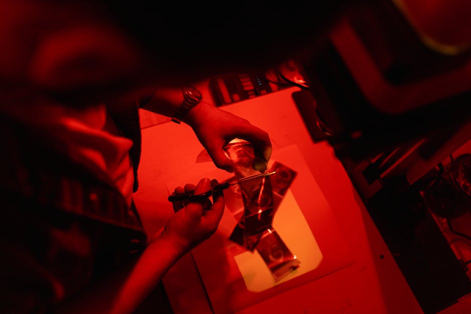 Sviluppo competenze uniche: Mani che tagliano pellicola in camera oscura, simbolo di precisione e abilità distintive nel lavoro professionale.