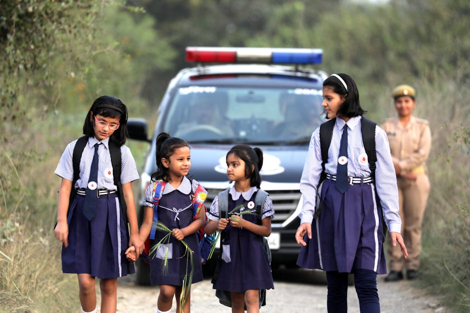 Studentesse indiane in uniforme scolastica con auto della polizia sullo sfondo, sicurezza scolastica e supporto generazionale al decreto sicurezza.