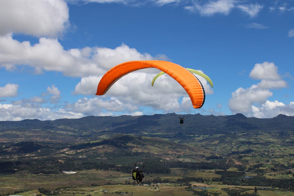 Parapendio arancione e verde su paesaggio montano: la prospettiva di chi è alto 6 piedi e domina il mondo