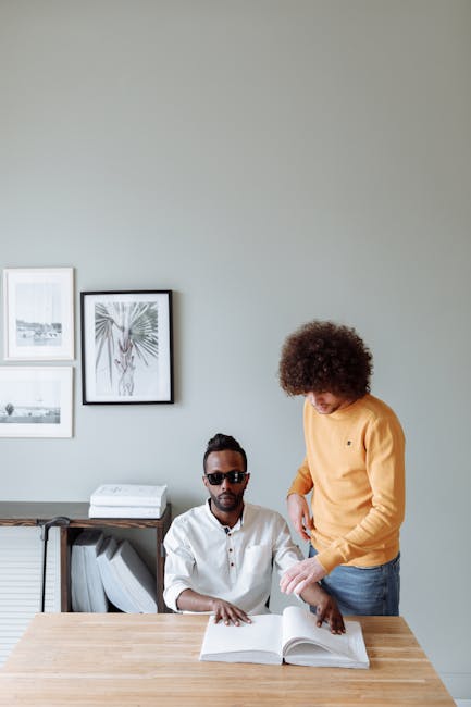 Assistenza ATA e alunni con disabilità: un ragazzo aiuta un compagno non vedente a leggere un libro in braille a scuola.