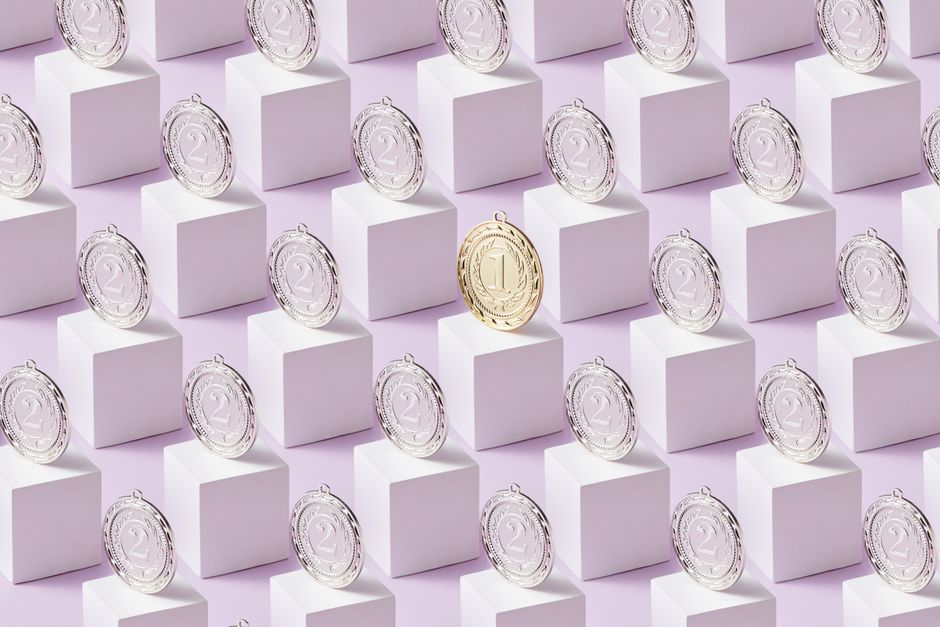 Medaglia d'oro in primo piano su cubi bianchi, circondata da medaglie d'argento, simboleggia il successo nei concorsi pubblici