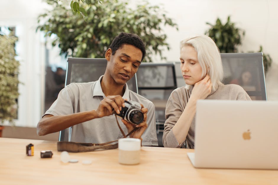 Due persone che lavorano insieme, un uomo con una macchina fotografica e una donna con un laptop, concetto di collaborazione e angoli
