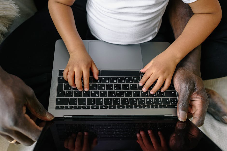 Bambino che impara a usare il computer con l'aiuto del genitore, promuovendo l'educazione familiare e la collaborazione digitale