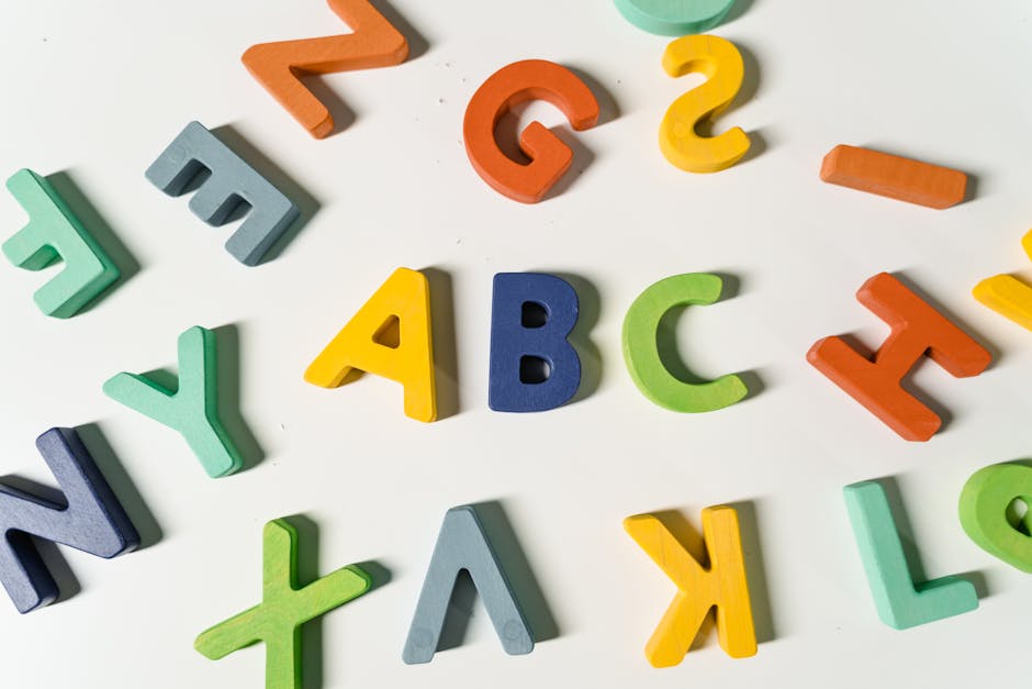 Lettere colorate in legno sparse su sfondo bianco, rappresentazione visiva dell'alfabeto per l'apprendimento Montessori e l'istruzione consapevole.