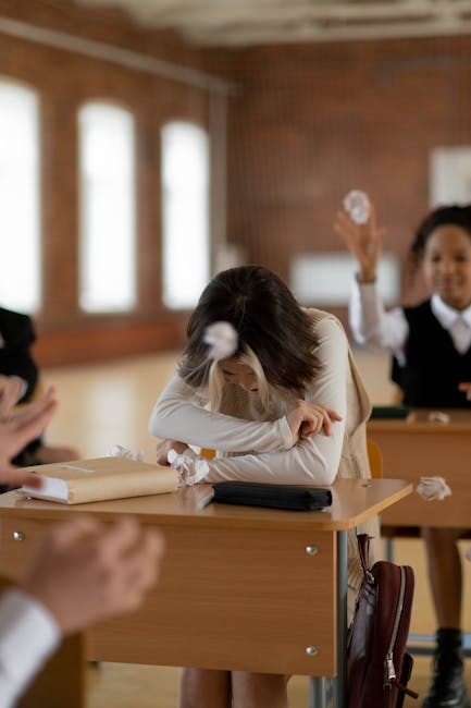 Studentessa affranta in classe durante lancio di palle di carta, metafora del dolore e trauma post sparatoria scolastica in Canada