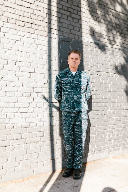 Uomo in uniforme mimetica appoggiato al muro: celebrare l'autenticità contro il body shaming