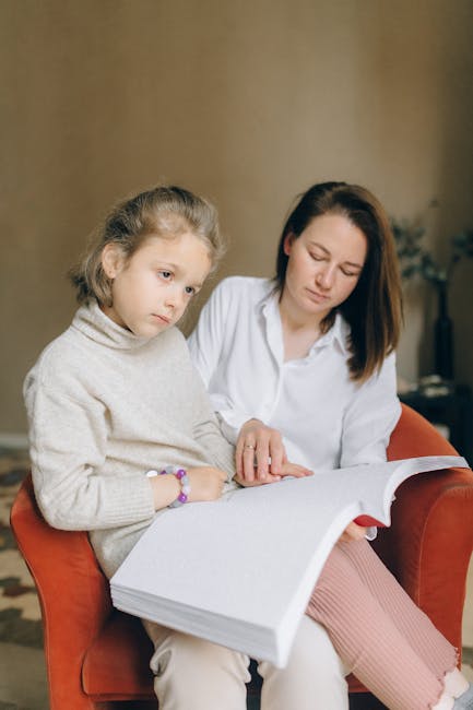 Bambina con disabilità visiva legge con l'aiuto di un'assistente ASACOM, cruciale per l'inclusione scolastica e il supporto familiare.