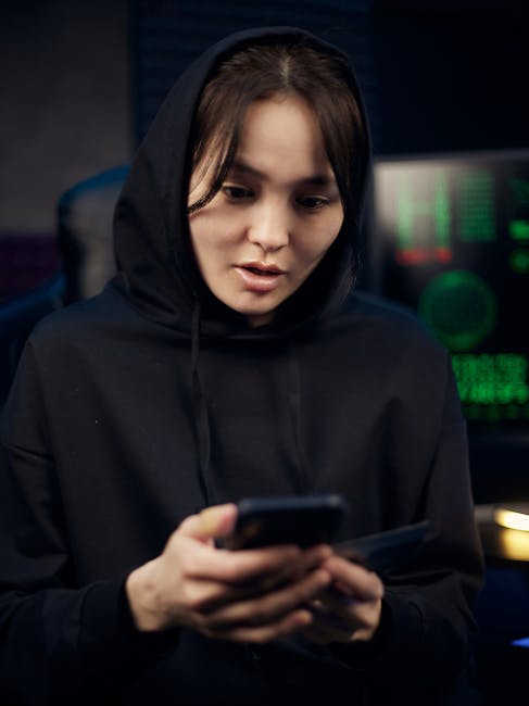 Donna con felpa con cappuccio usa smartphone: attenzione alla sicurezza online e protezione dei dati personali.