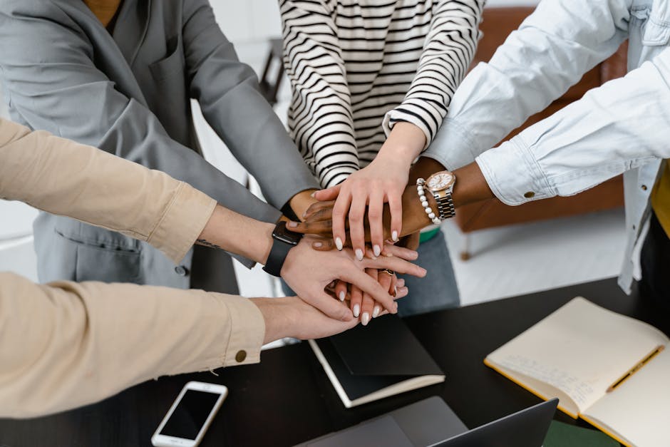 Mani unite di un team multietnico: simbolo di collaborazione e vantaggi dell'assicurazione collettiva per i dipendenti
