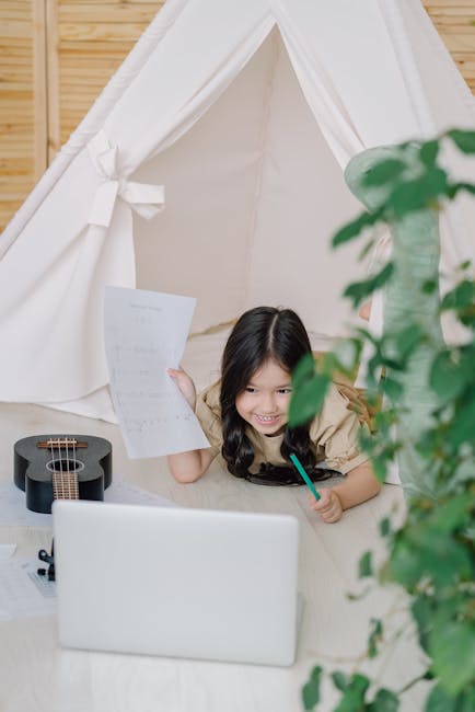 Bambina sorridente studia con laptop e ukulele in tenda, esempio di funzione di supporto per l'apprendimento e la crescita.