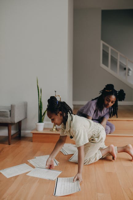 Bambine che organizzano spartiti musicali sul pavimento in legno, attività musicale creativa per bambini, apprendimento divertente.