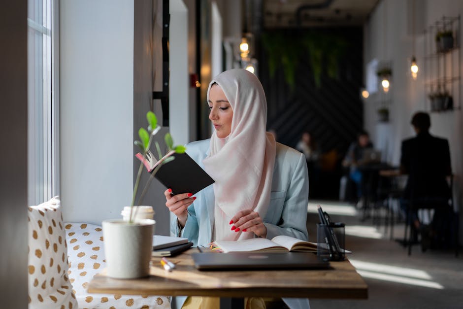 Donna con hijab studia in un caffè luminoso, esempio di apprendimento personalizzato per adulti e metodologie didattiche differenziate.