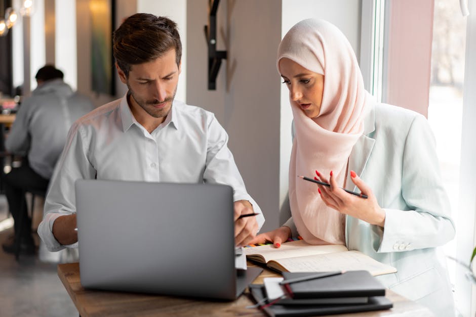 Uomo e donna con hijab collaborano su laptop per materiali formativi accessibili e inclusivi