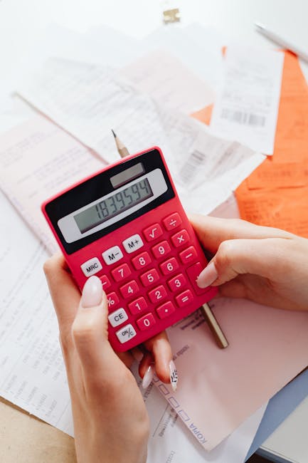Calcolatrice rossa in mano su documenti finanziari, simbolo di gestione del portafoglio e pianificazione finanziaria efficace