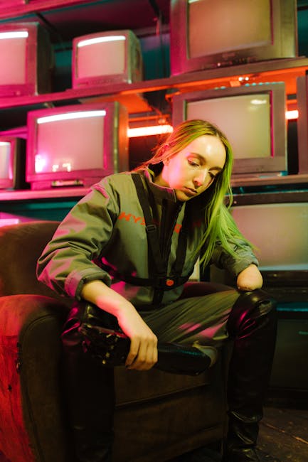 Donna con tuta futuristica seduta su poltrona tra schermi TV, metafora di innovazione tecnologica e corrente elettrica del futuro