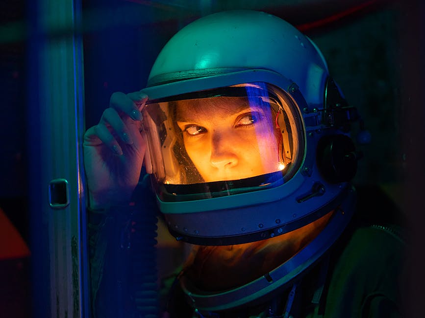Astronauta donna con casco guarda fuori, illuminazione futuristica, esplorazione spaziale e tecnologie avanzate per l'umanità