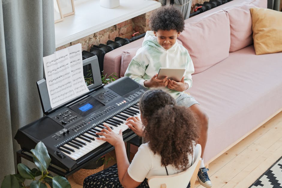 Ragazza suona tastiera digitale mentre ragazzo usa tablet, esempio di pedagogia e tecnologia nell'educazione musicale moderna.