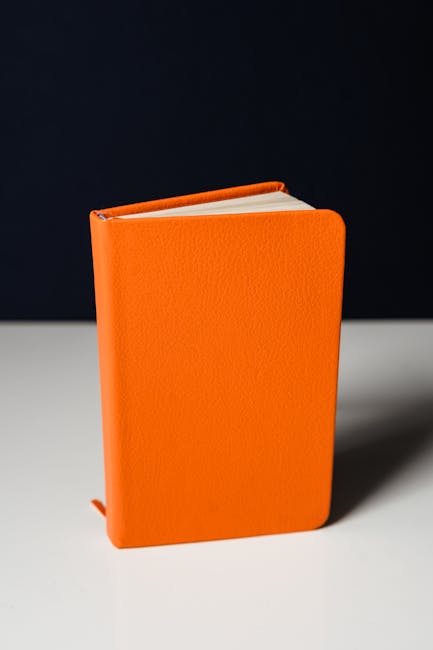 Libro arancione su tavolo bianco, metafora del piano di studi Unifi e del futuro accademico degli studenti universitari.