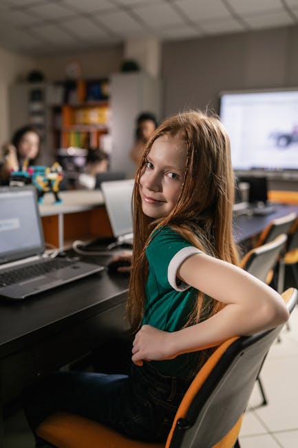 Ragazza sorridente in classe con computer, esempio di istruzione scolastica per la generazione green e la sostenibilità.
