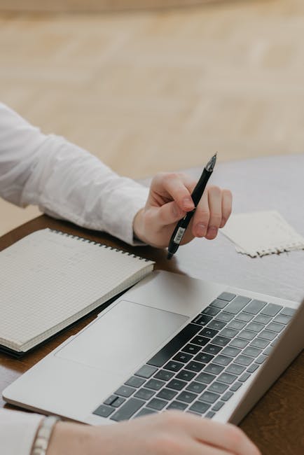 Persona che prende appunti su un quaderno accanto a un laptop, riflettendo sulla gestione dei dati personali e la sicurezza online.