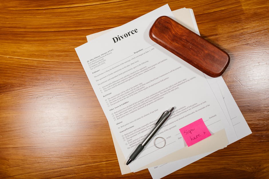 Documento di divorzio con penna e anello su tavolo di legno. Richiamo alla fine di un matrimonio e implicazioni legali.