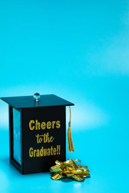 Scatola regalo a forma di tocco di laurea con scritta Cheers to the Graduate, legata all'articolo sullo scandalo al liceo.
