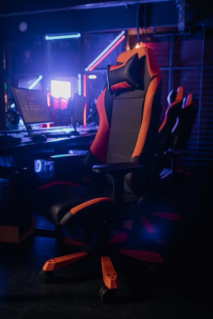 Sedia da gaming ergonomica arancione e nera, postazione PC illuminata, comfort e design per massimizzare la differenza di potenziale nel gioco.