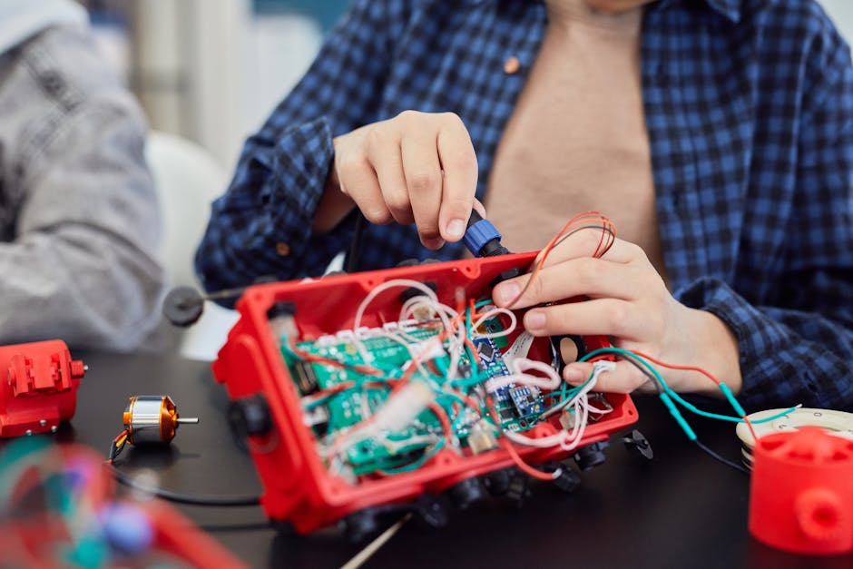 Studente che lavora su un progetto di robotica con scheda elettronica e fili colorati, esempio di tecnologia per l'insegnamento unico.