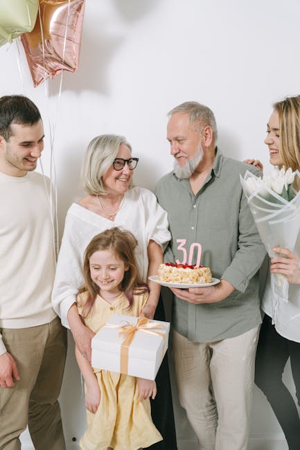 Nonni e nipoti condividono una torta di compleanno e un regalo, un rituale di merenda intergenerazionale che crea legami affettivi.