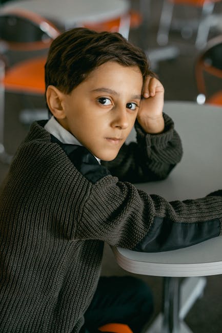 Ragazzo pensieroso a scuola, possibile caso di rifiuto scolastico legato a disabilità e discriminazione. Focus sull'inclusione.