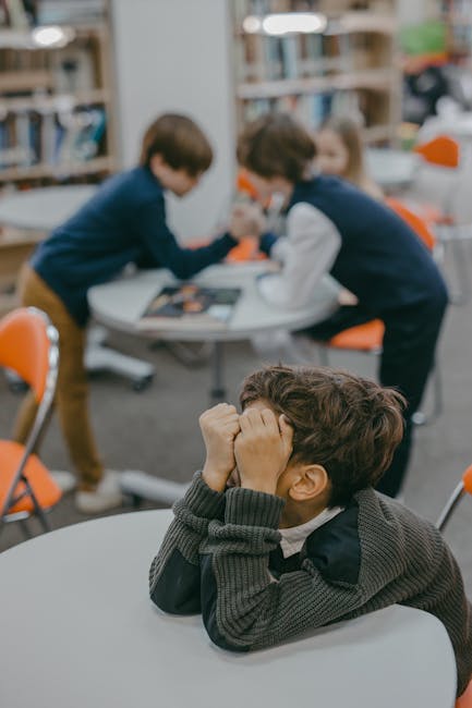 Ragazzo in difficoltà emotiva con compagni sullo sfondo, possibile vittima di bullismo scolastico e problemi di tutela emotiva.