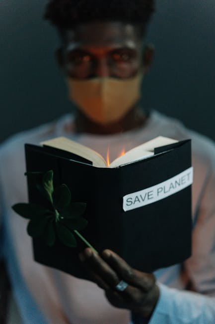 Uomo con mascherina tiene libro con scritta Save Planet e pianta, simbolo educazione biodiversità e futuro sostenibile.