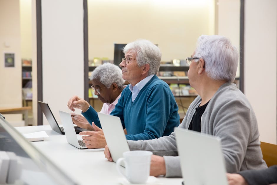 Persone anziane che partecipano a un corso di elettronica digitale con laptop per sviluppare competenze informatiche.