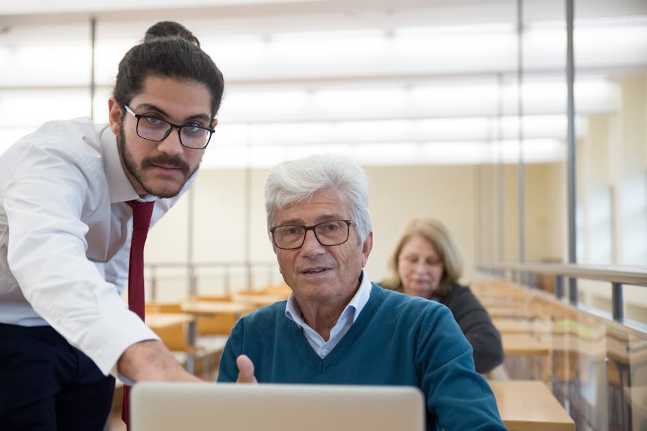 Insegnante spiega meditazione tecnologica a studente senior con laptop in classe, metodo innovativo per l'apprendimento