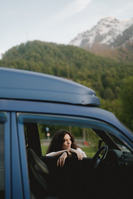 Donna in auto con portapacchi ascolta musica in viaggio, sfondo montano per un'esperienza sensoriale unica e divertente.