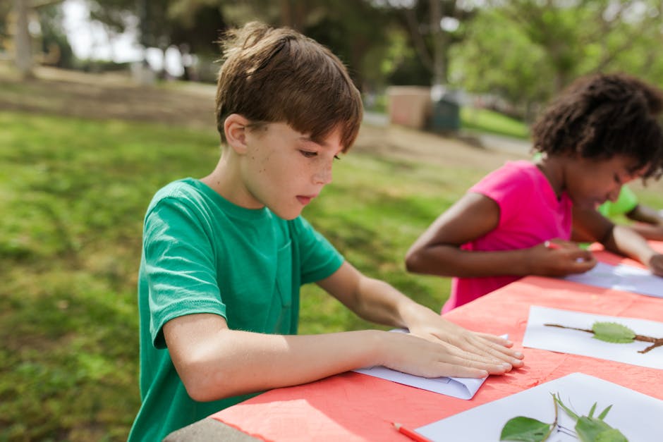 Bambini impegnati in attività creative all'aperto, alternativa all'ora di religione, con foglie e disegni su carta.